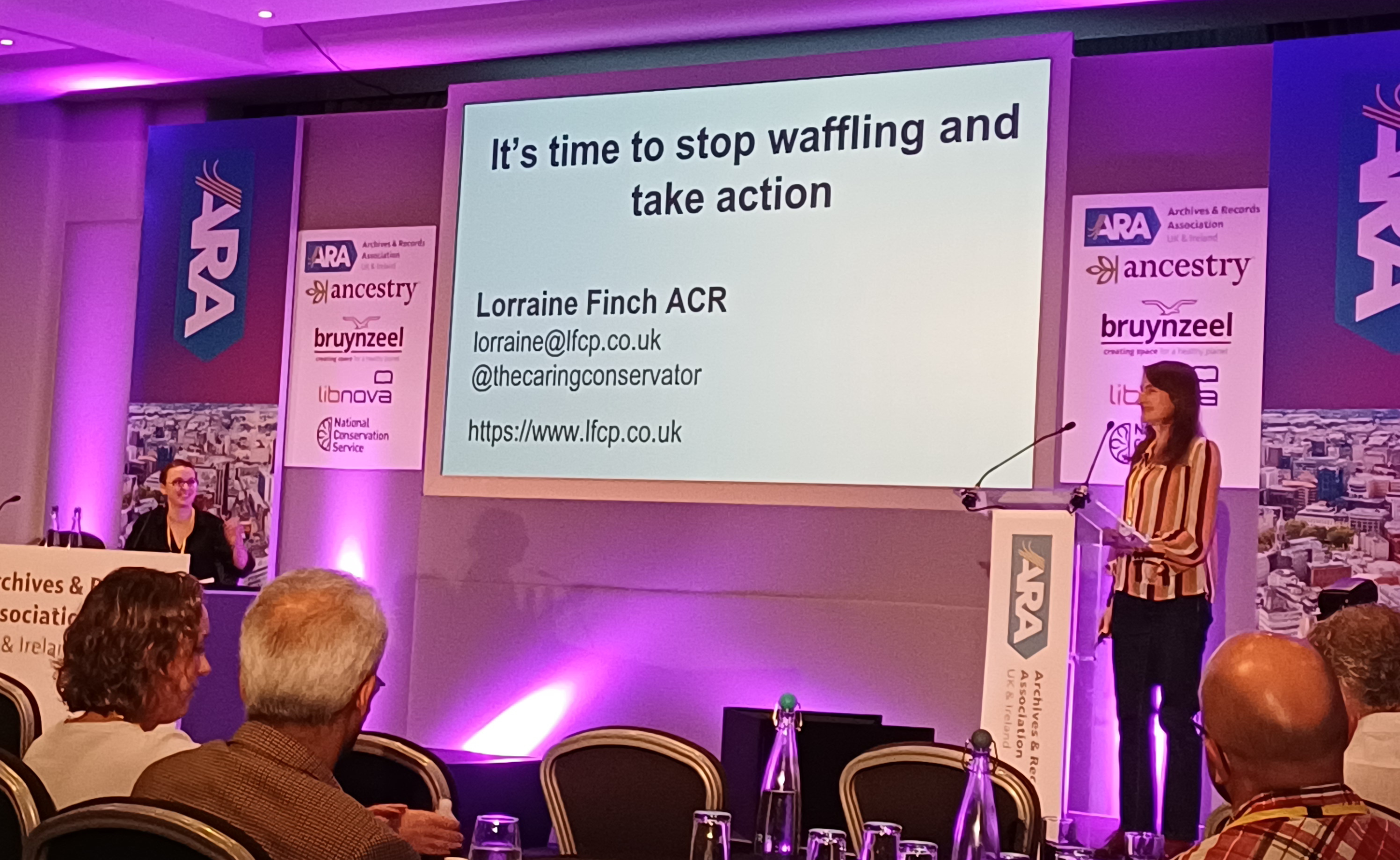 Lorraine Finch presenting a conference keynote. On the presentation slide is the heading "It's time to stop waffling and take action".