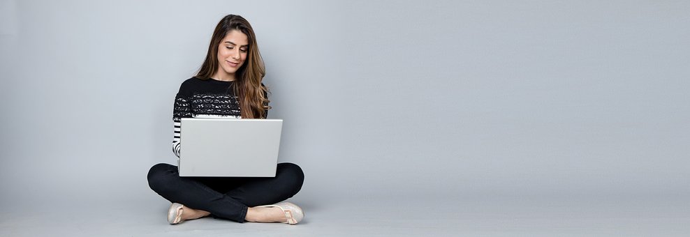 A women sitting cross legged on the floor using a laptop