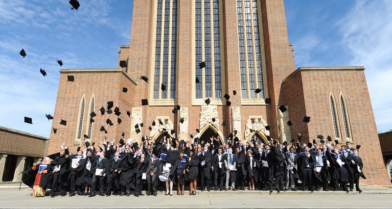 University of Surrey graduates throwing their mortar-boards in the air outside Guildford Cathedral