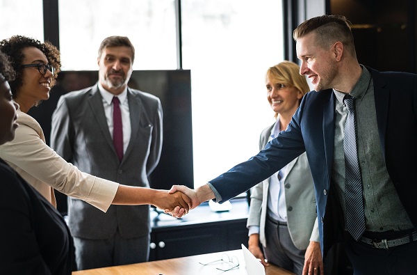 A woman and man shaking hands, with three other people looking