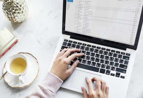 Person typing and drinking tea 