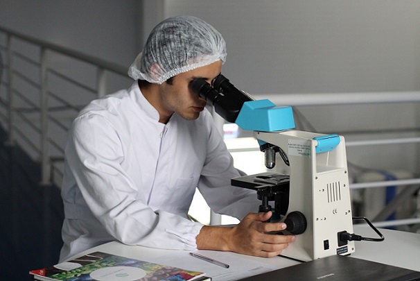 A lab technician looking into a microscope