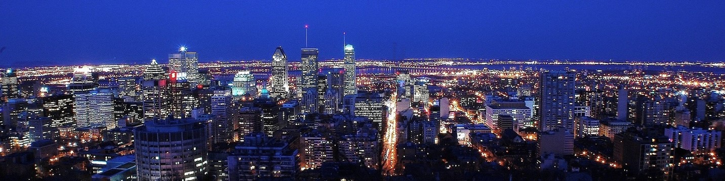  A panarama photo of the skyline of Montreal at night, with all the buildings lit up against a dark blue sky