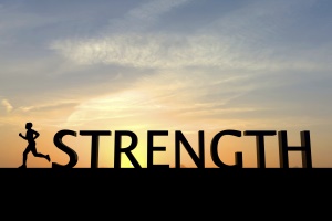 he word strength is silhouetted against a bright sunset sky. To the left of the word is a single human figure running towards the left of the image. The sky is orange at the bottom changing to blue at the top, there are some clouds in the sky.