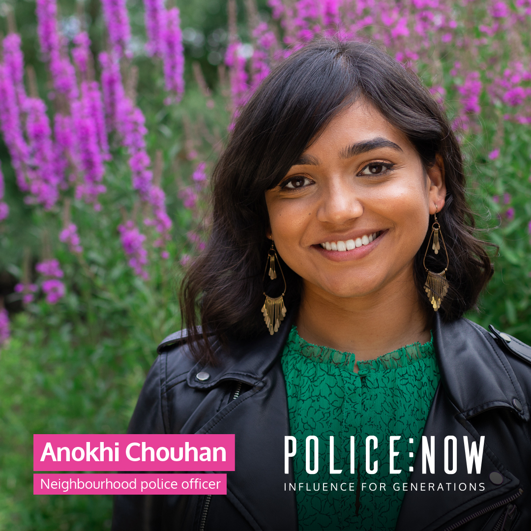 A photo of Anokhi Chouhan, Police Now, Neighbourhood police officer. She is smiling, in casual clothes, standing in front of some purple Foxgloves