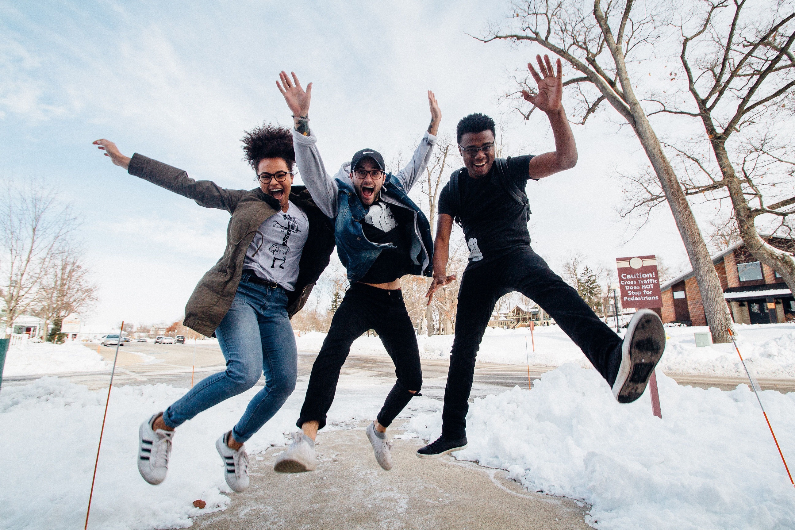 3 students jumping in the air with snow on the ground beneath them