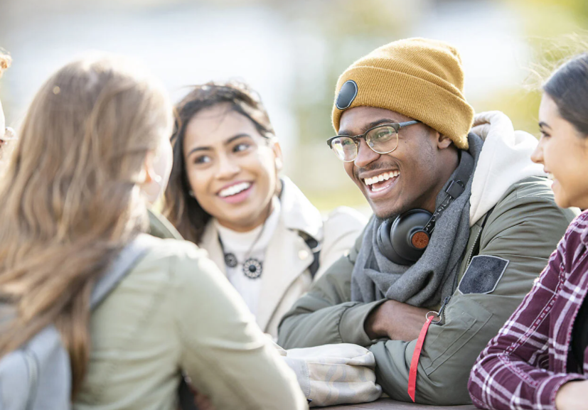 4 students chatting over a table outside