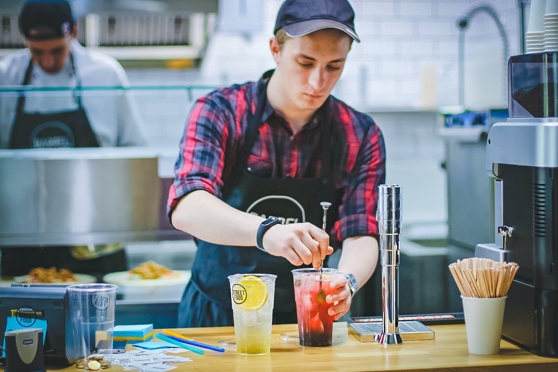 young man working in a restaurant. He is making a drink