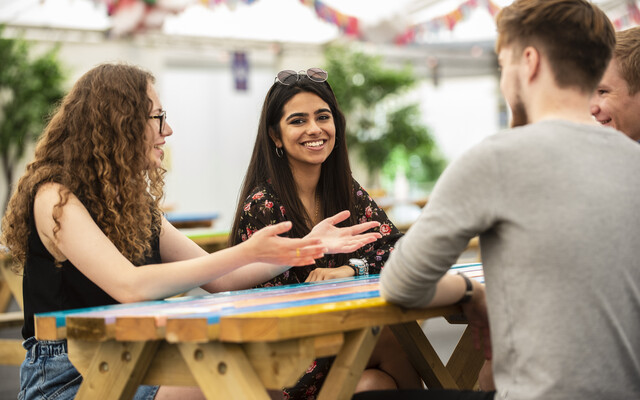 Surrey students chatting at a table.