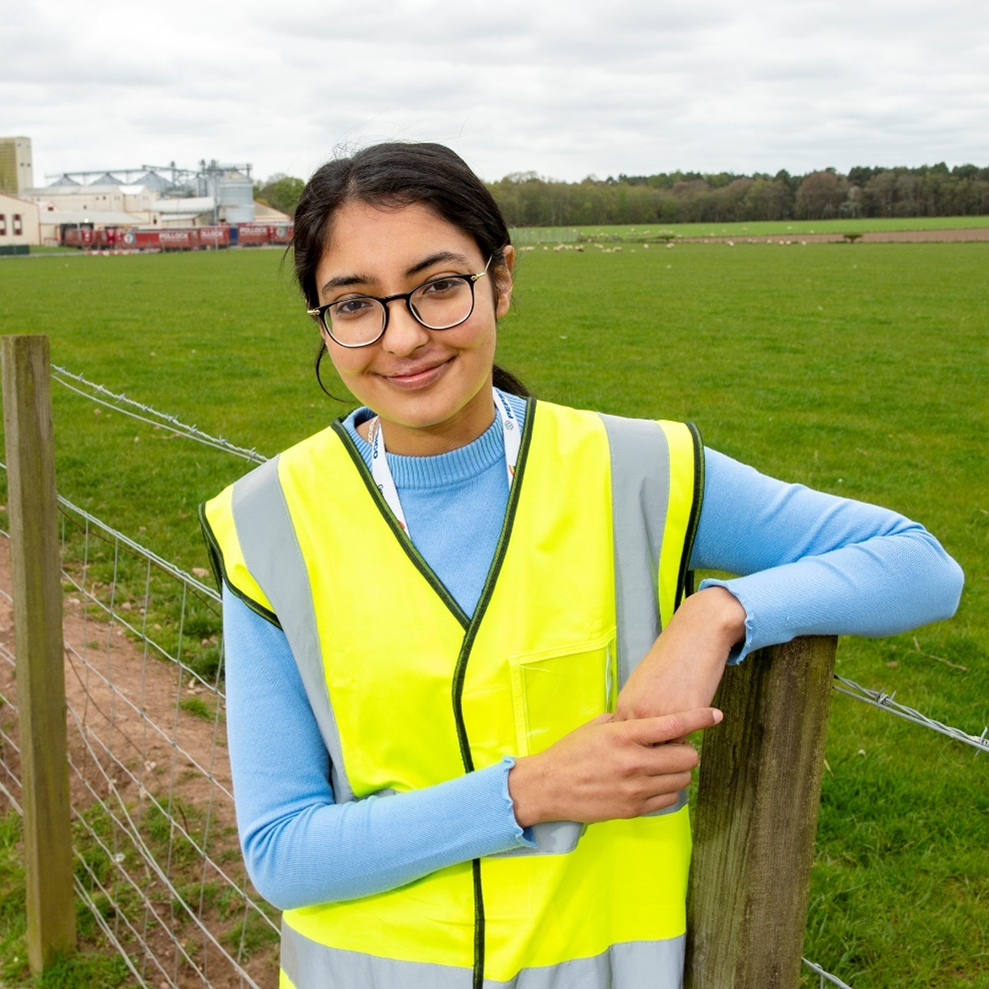 Sumreen wearing a high viz jacket by a fence