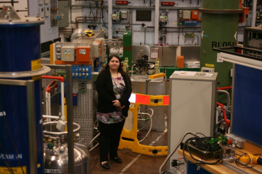 Image of the student standing in front of a large scientific instrument