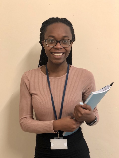 Adesuwa at work, wearing lanyard and holding books