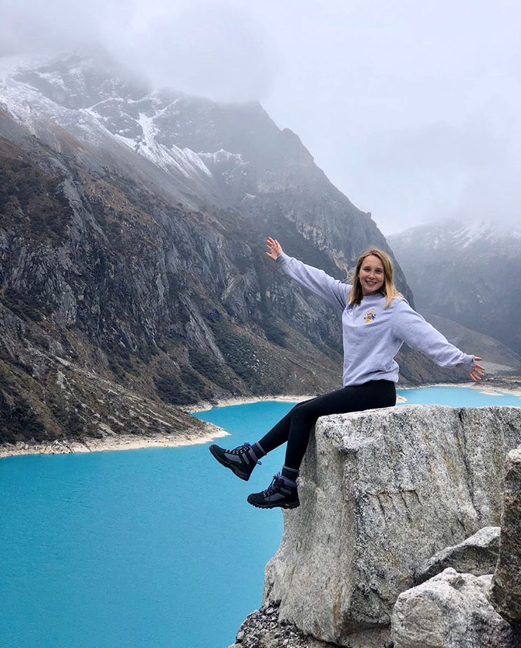 Picture of me sitting on a rock by a very blue lake
