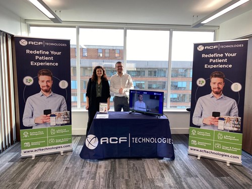 Two people standing behind a booth at a healthcare conference.