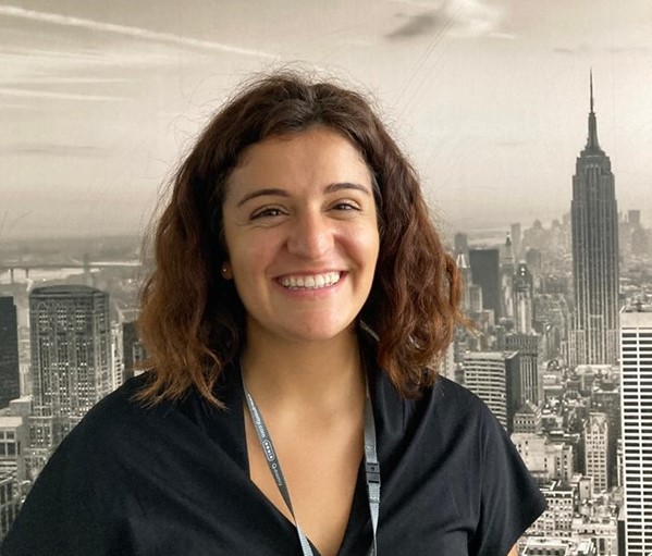 Alessia standing in the podcast studio in front of a New York wallpaper.