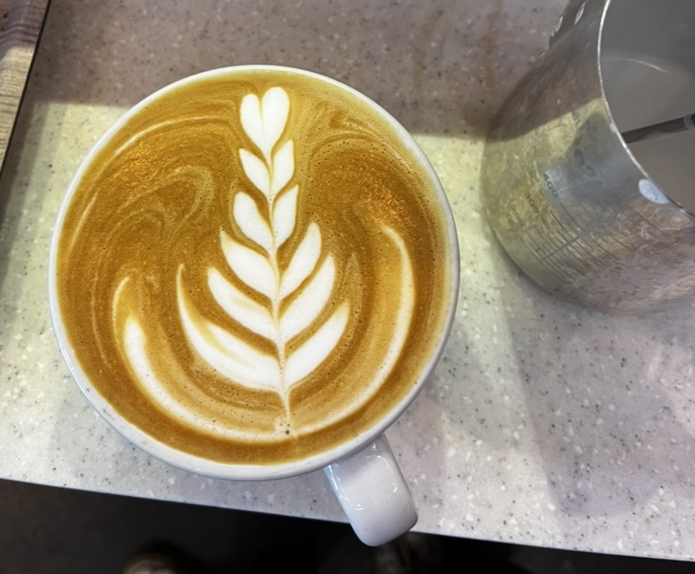 A cappuccino with a leaf emblem in the foam