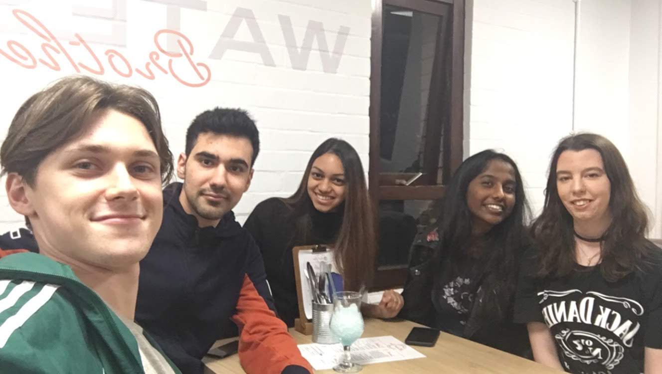 Group of friends taking a selfie sat in a cafe / bar. This is Wates House a catering venus on The University of Surrey campus.