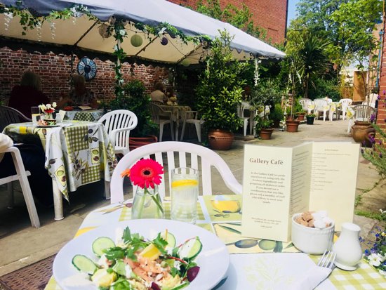 Gallery cafe Guildford, outside seating with vines, flowers and plants around cafe tables. Flowers on table 