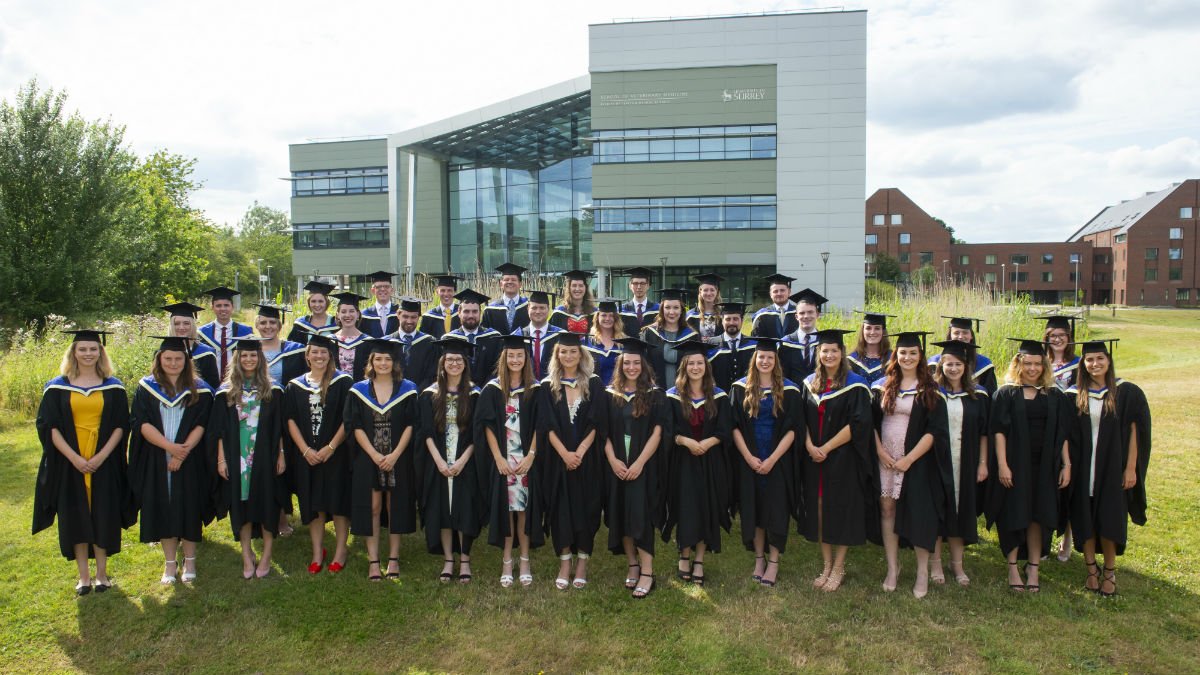 Vet graduates in cap and gown infront of the vet school having just graduated