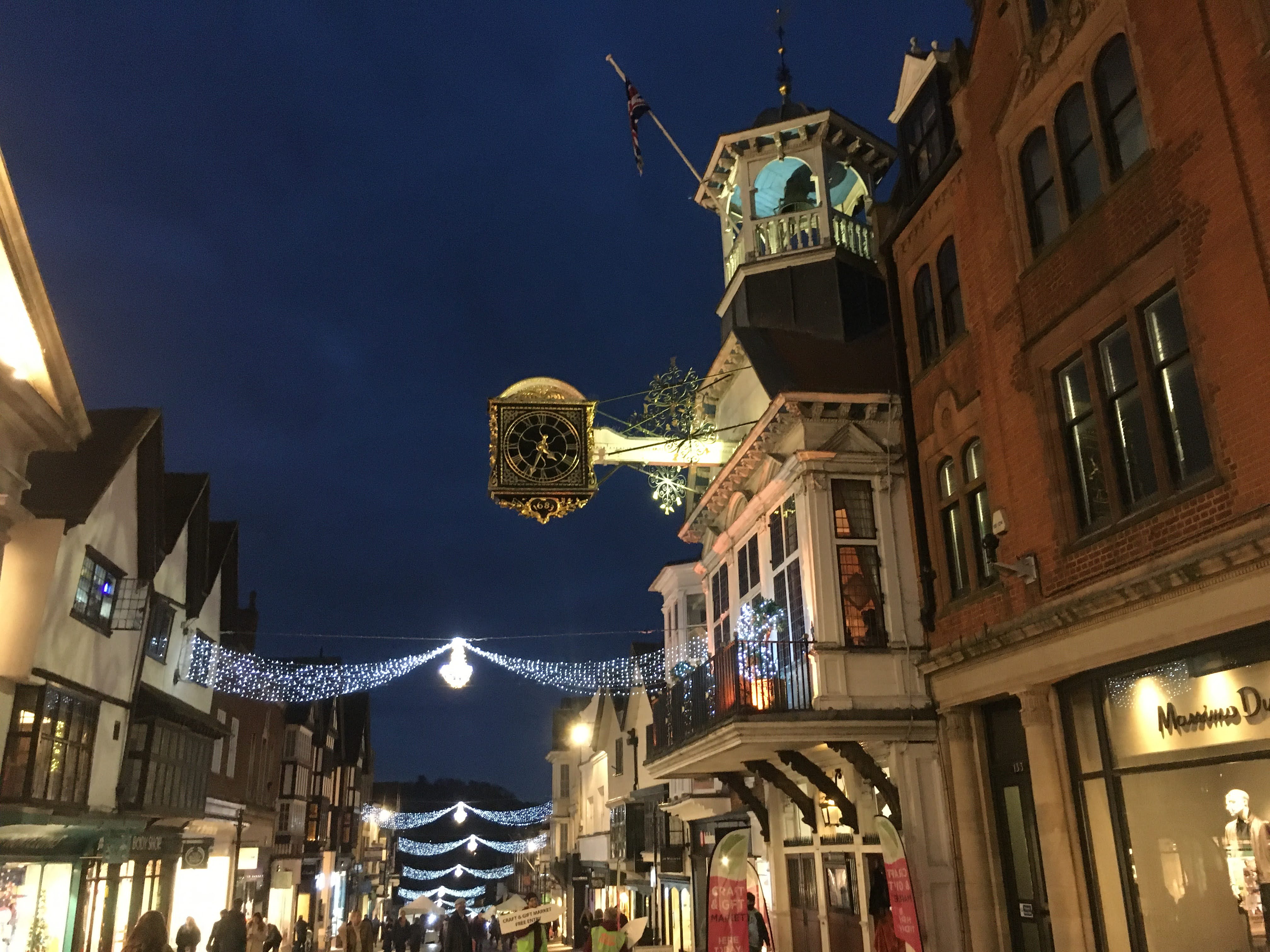 Guildford highstreet with Christmas decoration from either side of street in white and blue light. 