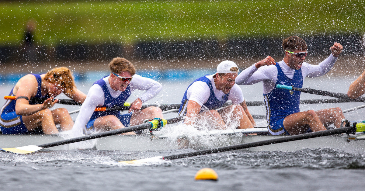 Mens rowing team quad celebrating winning a race by cheering and splashing water