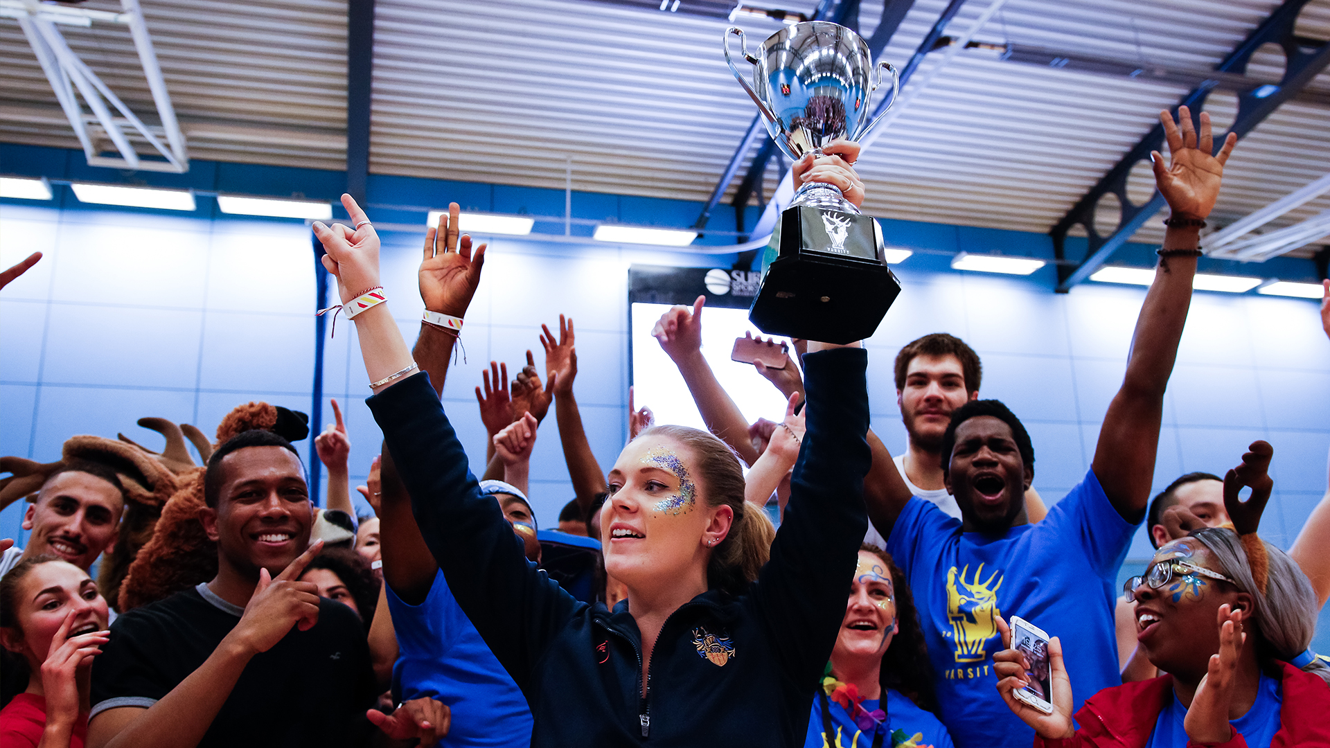 Students cheering and holding trophy after Surrey won Varsity.