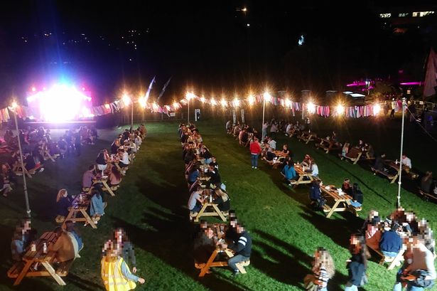 Students sat outside on benches by the Lake on Stag Hill campus enjoying the outdoor cinema